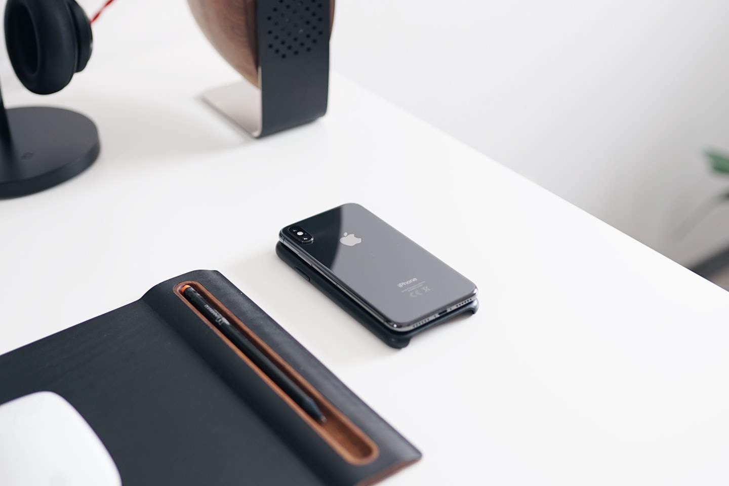 Modern desk essentials including a phone, notebook, and headphones on a white surface.